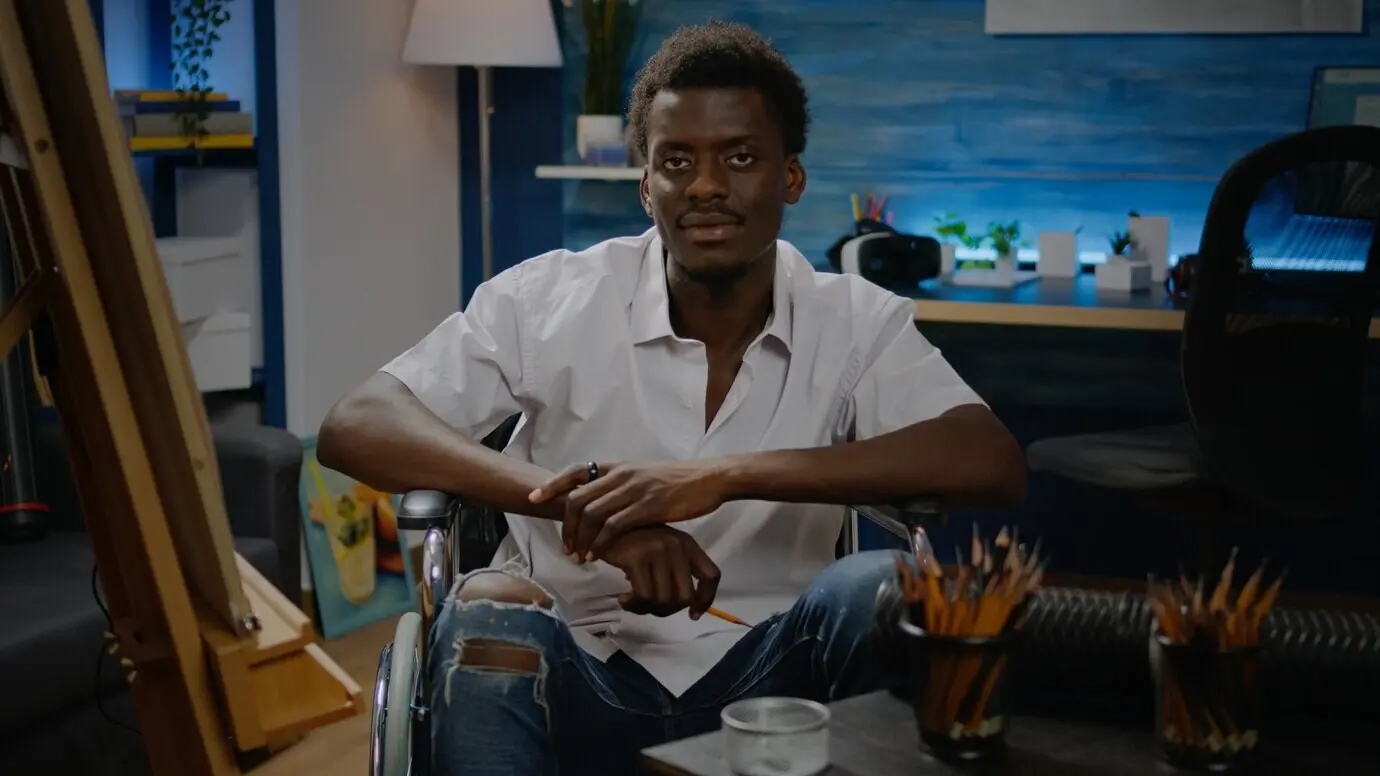 Schwarzer junger Künstler mit Behinderung, der Werkzeuge für modernes Zeichnen verwendet.